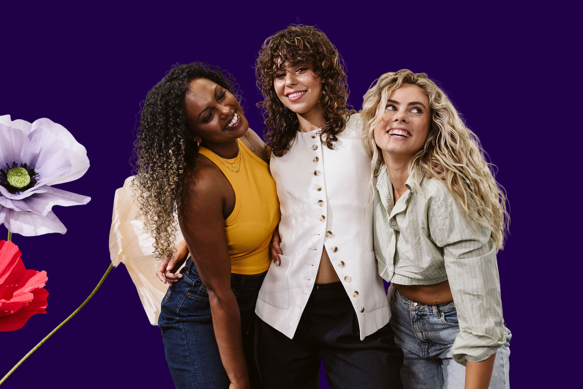 Three women with various curl types smiling in casual clothes