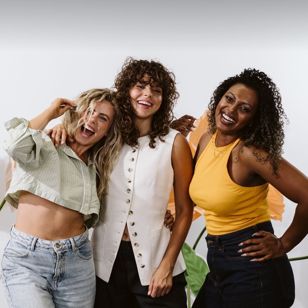 Women with wavy, curly and coily hair, different hair tones smiling