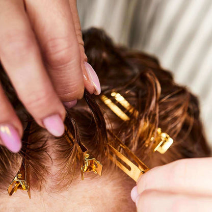 Clipping up a wavy hair fringe with gold clips