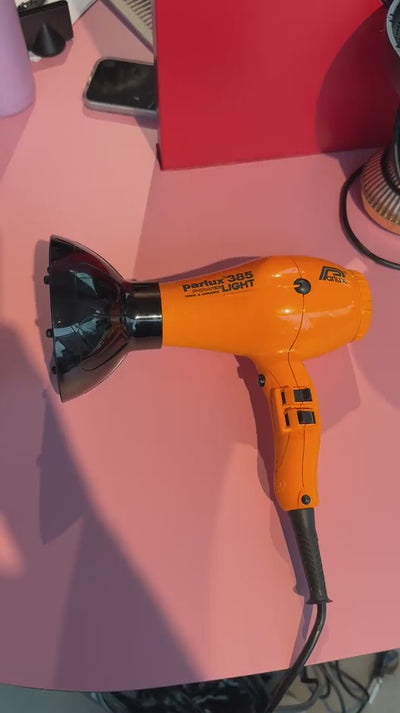 Yellow Parlux hairdryer being fitted to a curl flow diffuser in a salon 
