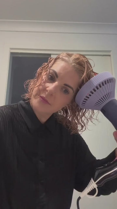 Lady drying her hair with a diffuser in a bathroom 