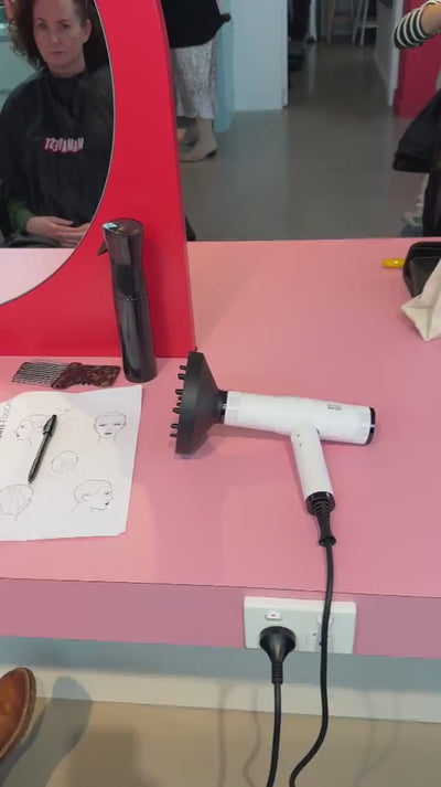 White Bondi Boost hair dryer being fitted to the curl flow diffuser in a salon 
